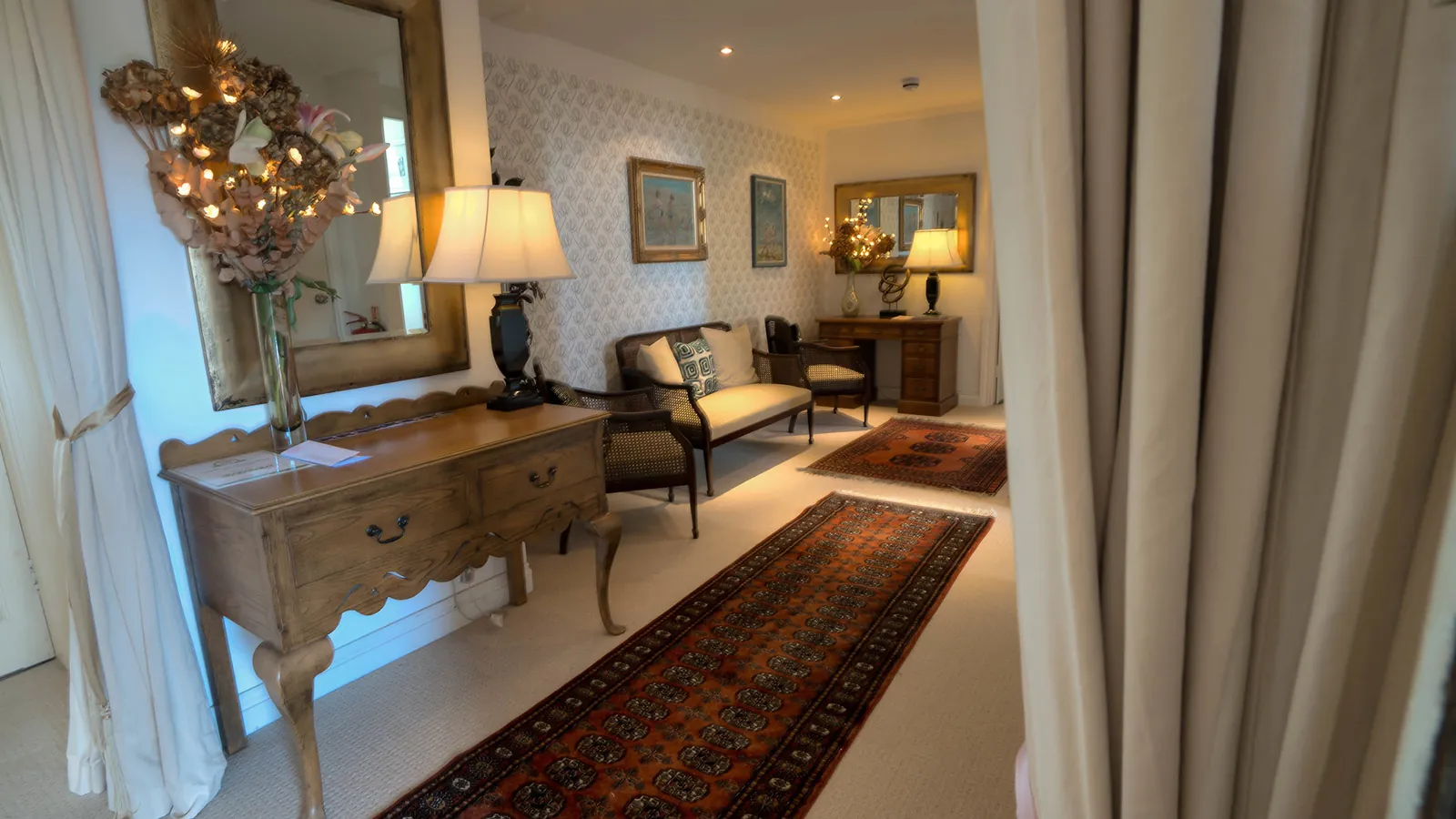 The panelled hall at Higher Faugan Parc with a period sideboard and rug